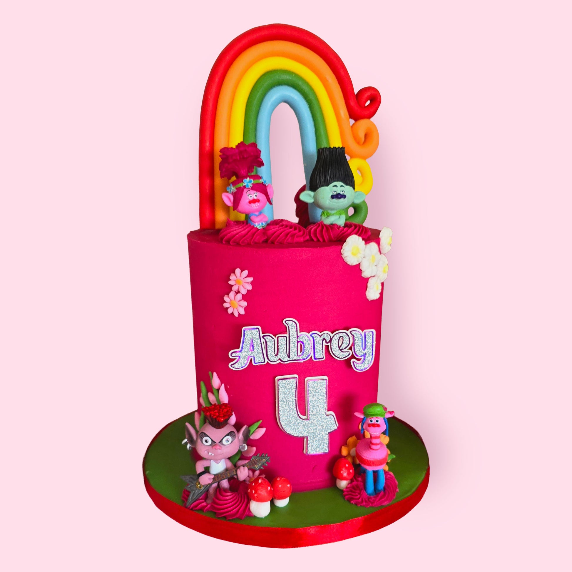 Bright Trolls-themed birthday cake with rainbow topper, cartoon figures, and personalised name “Aubrey” for 4th birthday