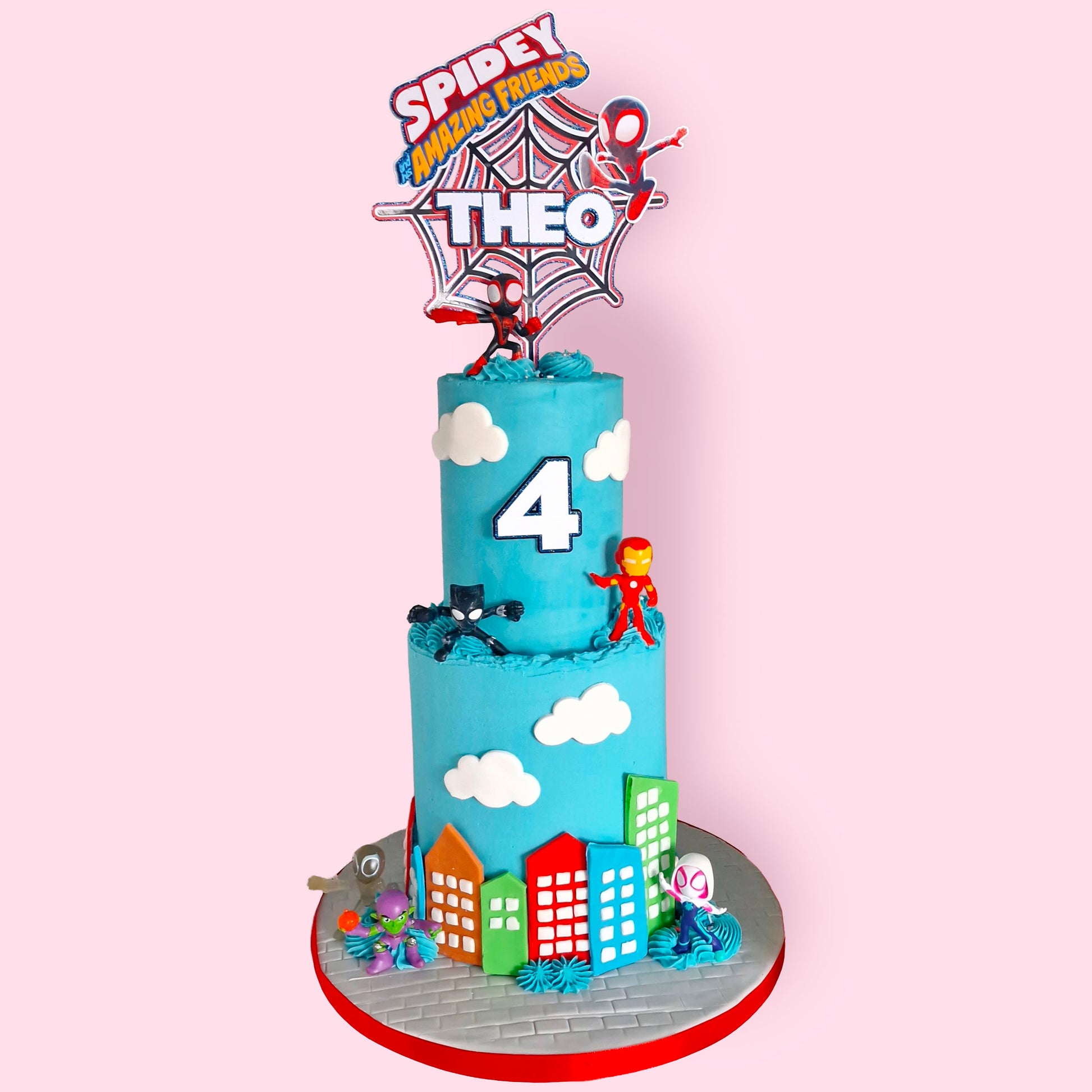Spiderman and superhero-themed two-tier birthday cake with cloud and city skyline decorations, personalised for Theo’s 4th birthday