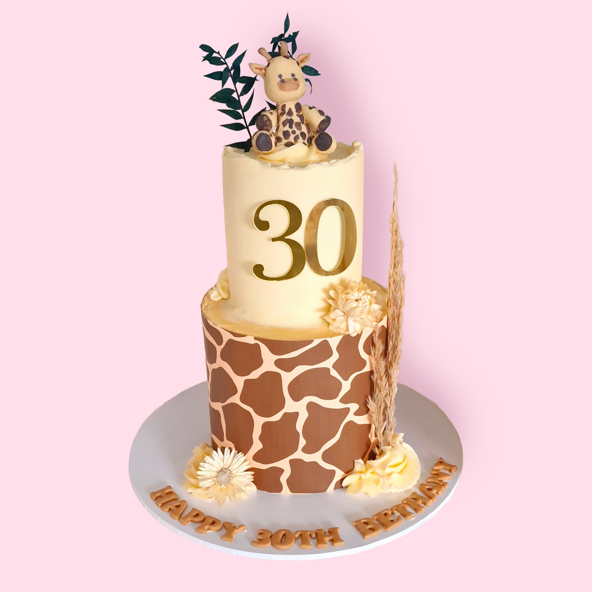 Two-tier giraffe print birthday cake with fondant giraffe topper, dried florals, and gold number 30 for Bethany’s celebration