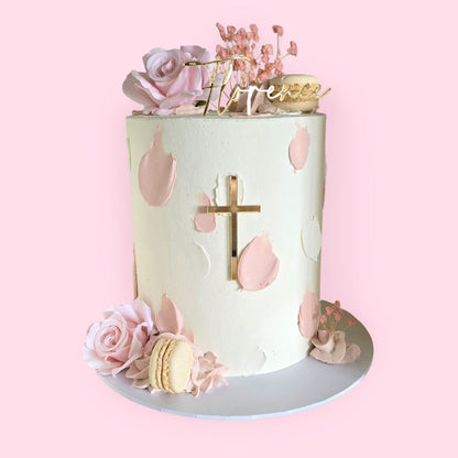 Elegant pink and white christening cake with gold cross, floral accents, and personalised name Florence