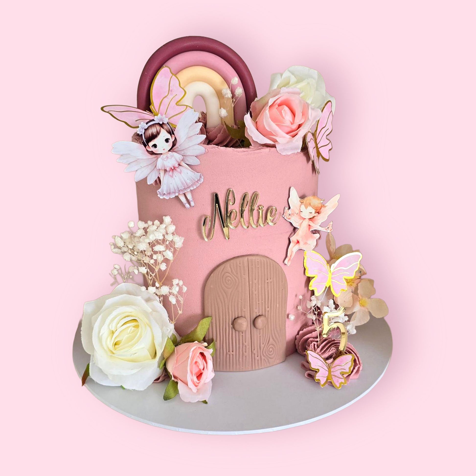 Custom fairy-themed birthday cake with pink decor, floral details, rainbow topper, and personalised name