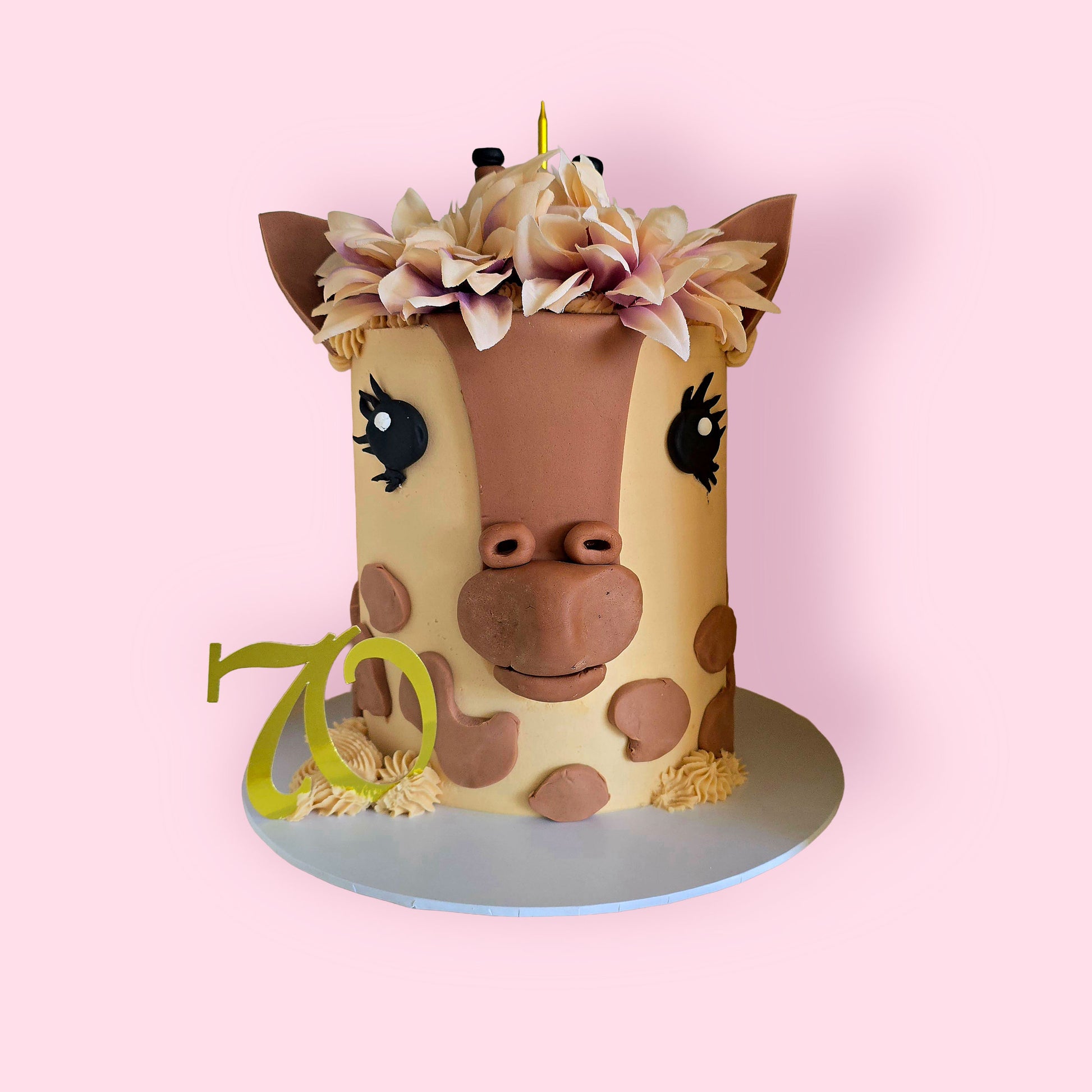 Custom giraffe-themed birthday cake with fondant animal face, floral crown, and number 70 topper