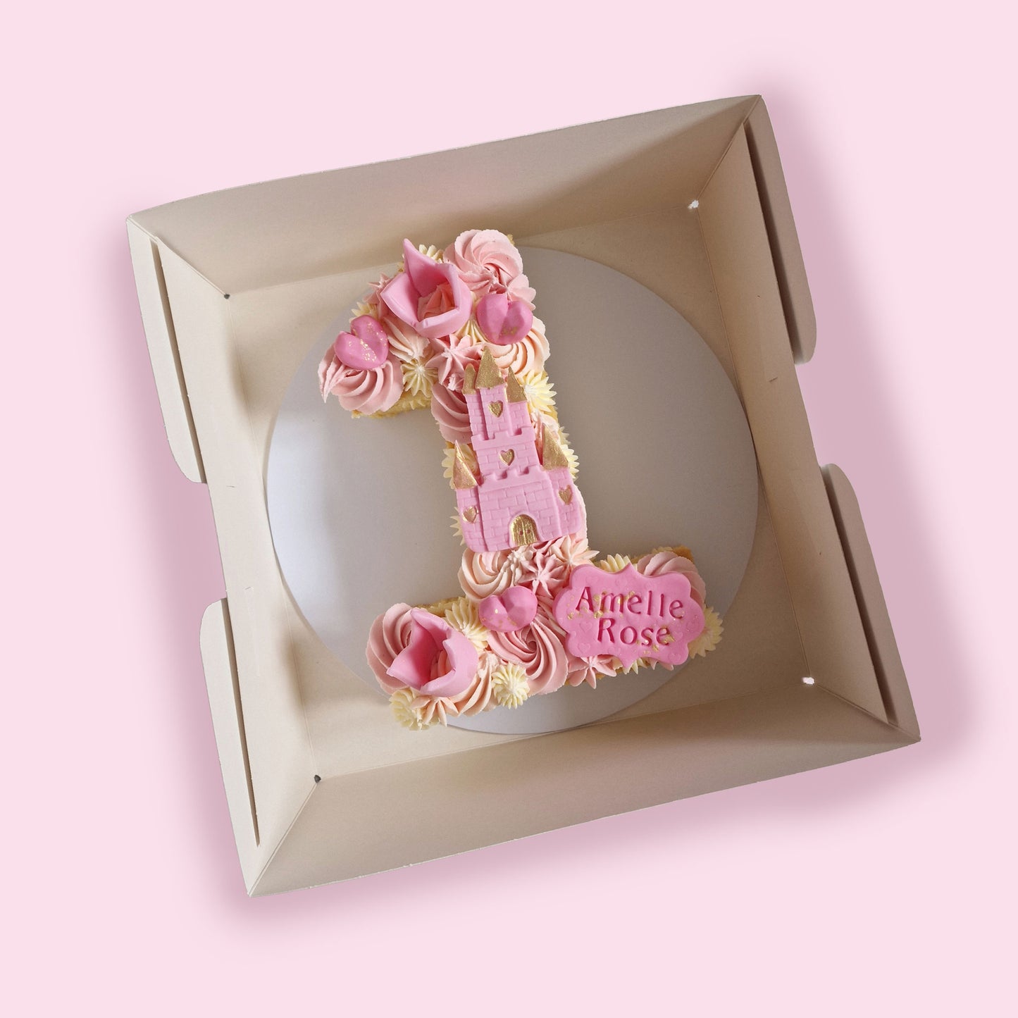 Princess-themed number 1 birthday cake with pink castle topper, hearts, and personalised name “Amelle Rose”