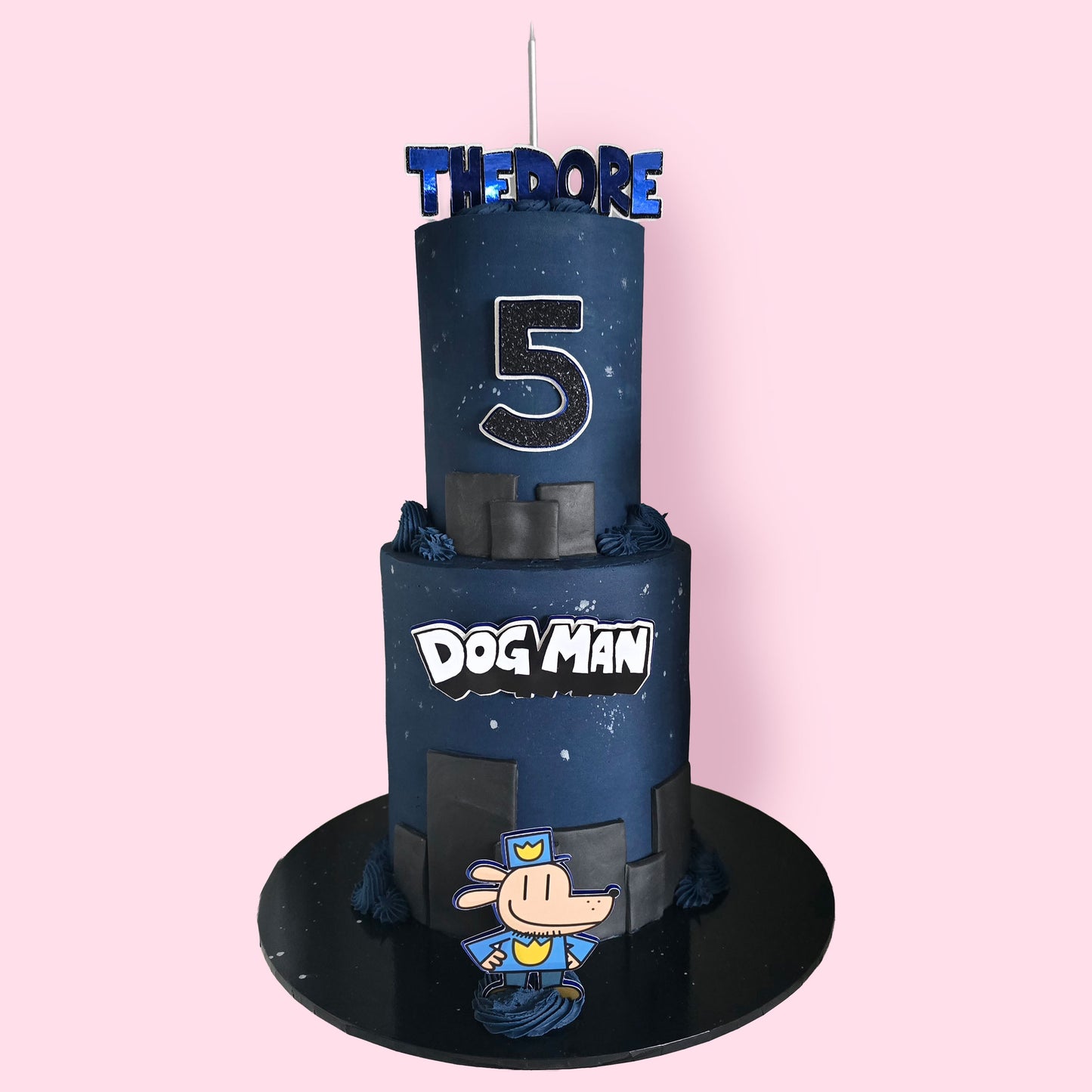 Custom Dog Man-themed two-tier birthday cake with black and navy blue fondant, cartoon topper,